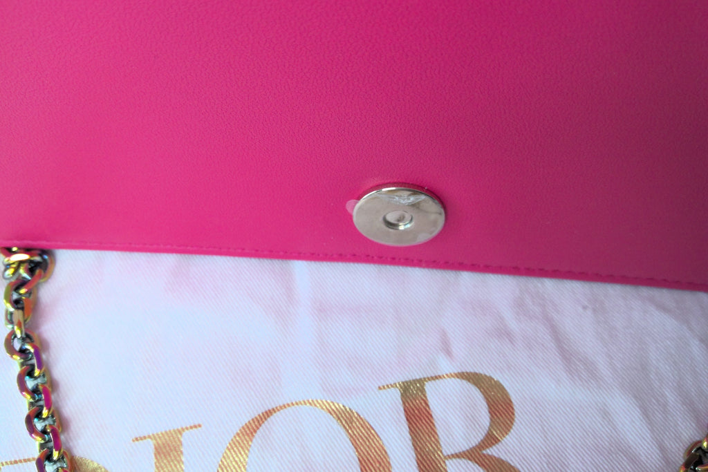 Close-up of a pink handbag with a gold chain and visible brand name.