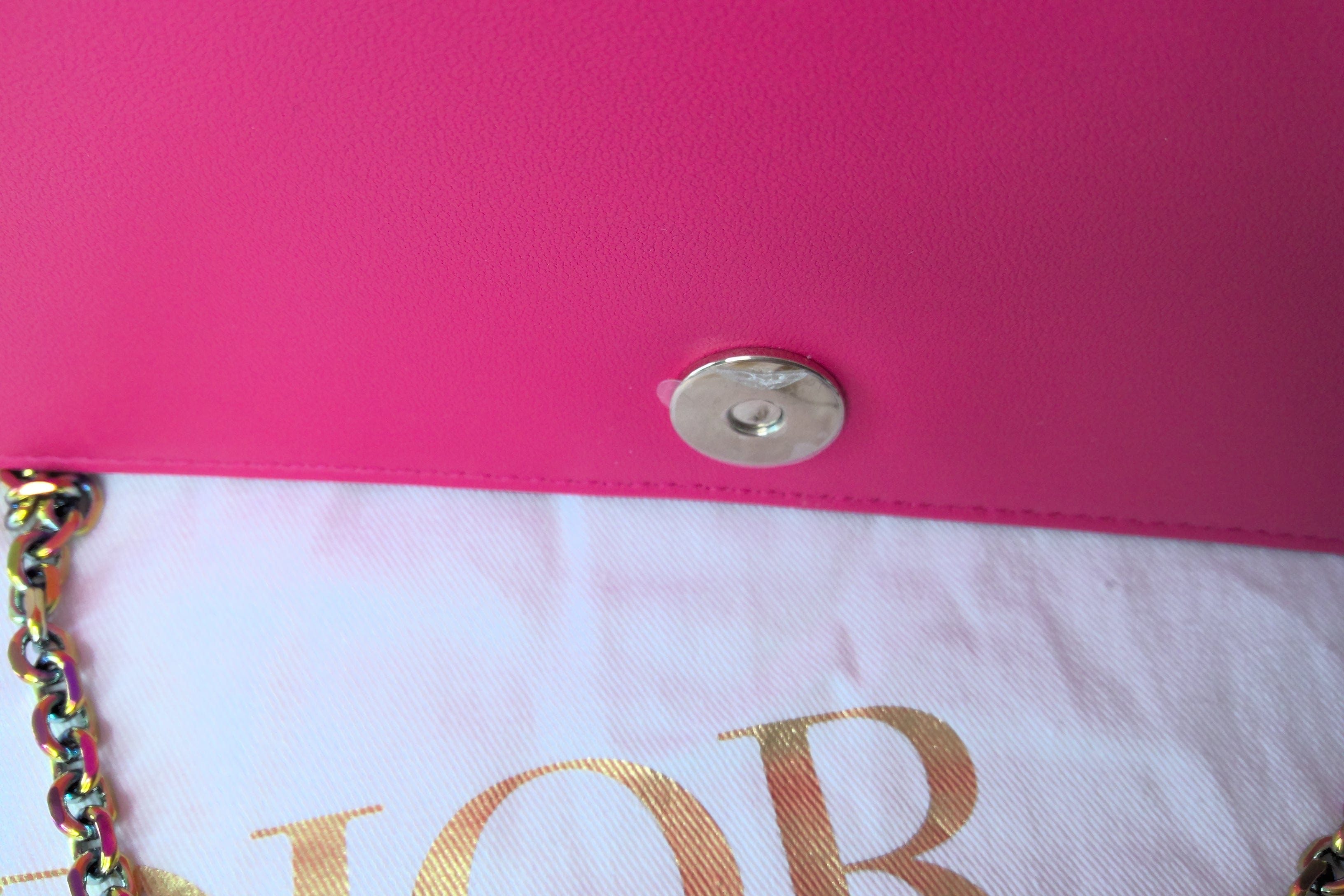 Close-up of a pink handbag with a gold chain and visible brand name.
