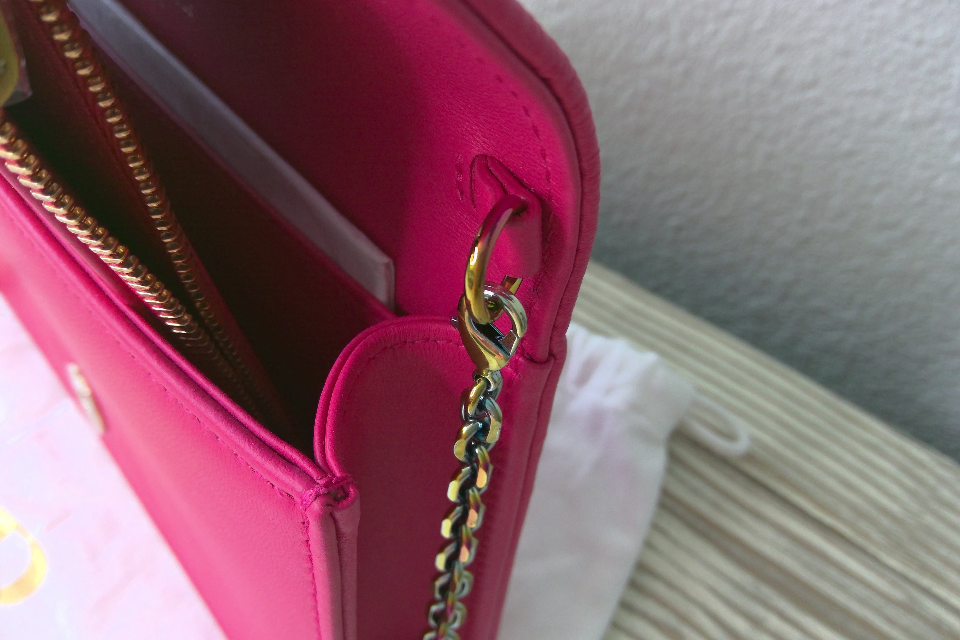 Close-up of a pink handbag with a gold chain detail on a neutral background