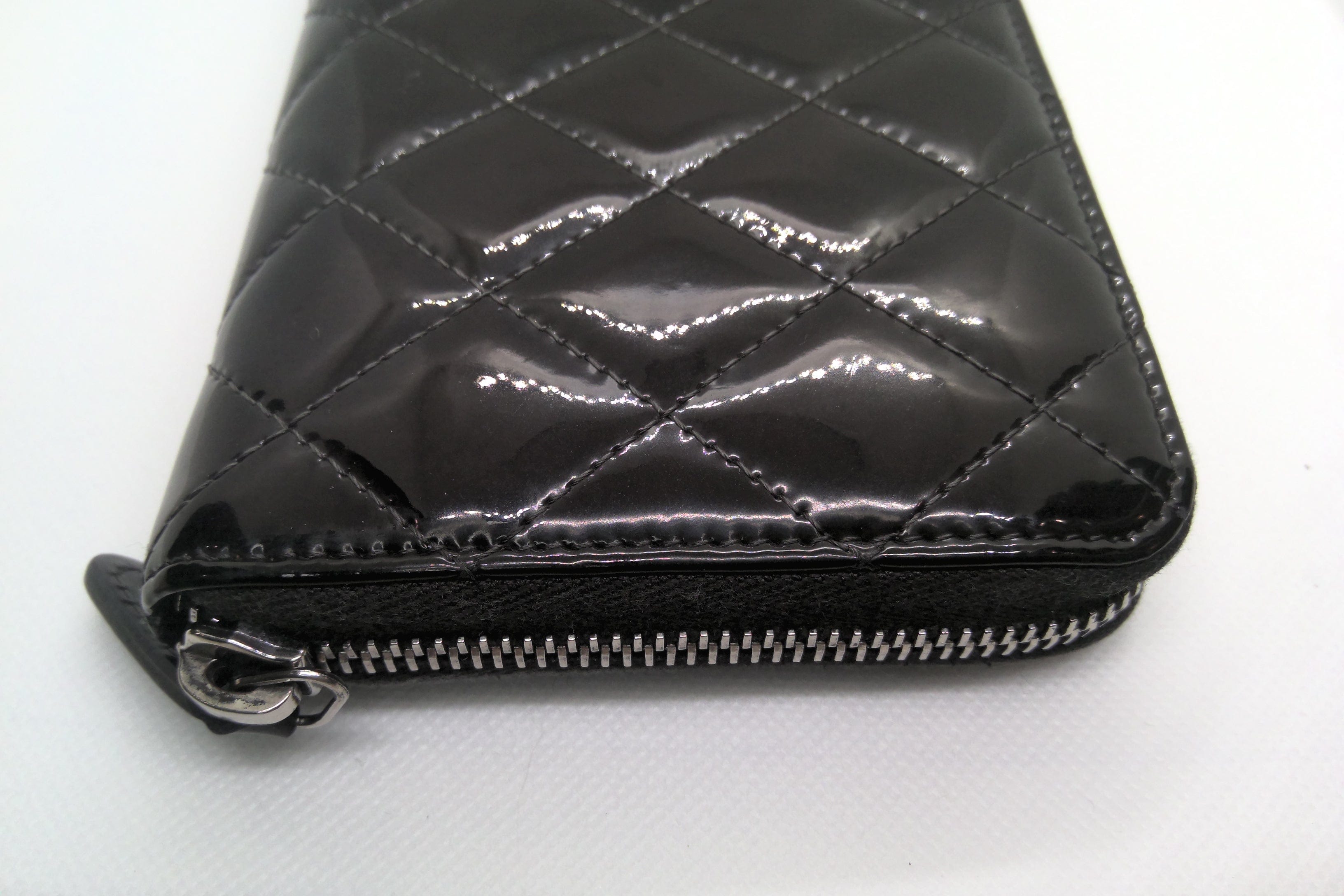 Black quilted wallet with a zipper on a white background