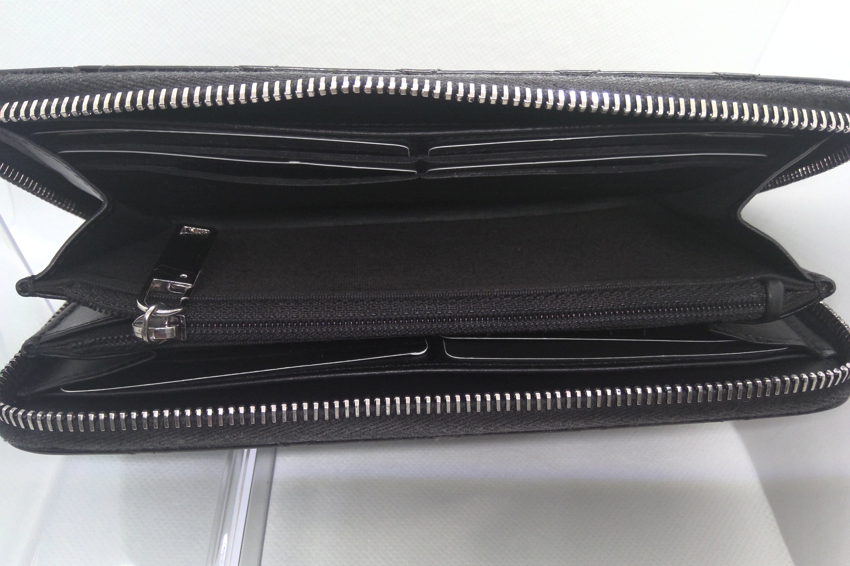 Black leather wallet with silver zipper on a white background