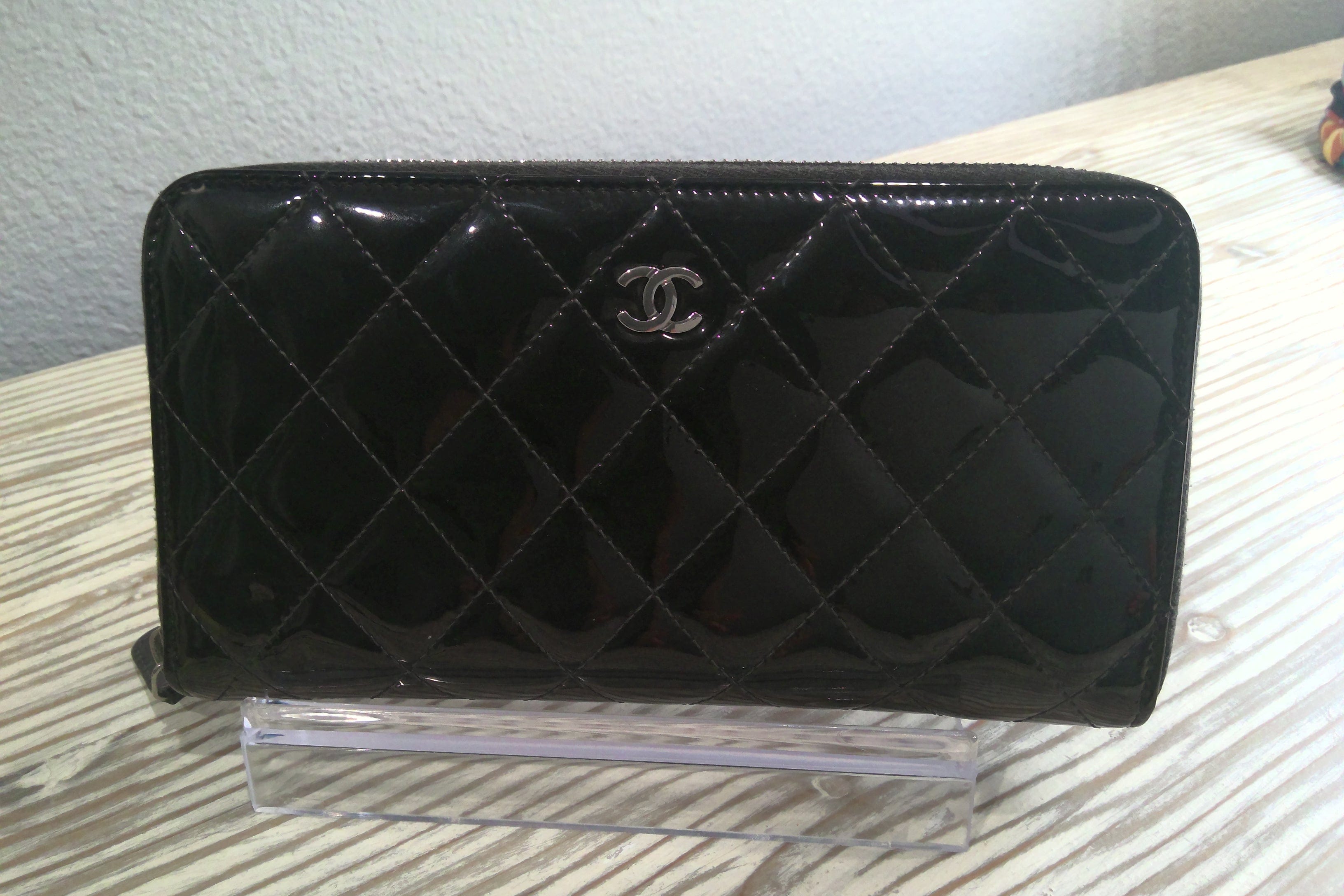 Black quilted wallet with Chanel logo on a white surface