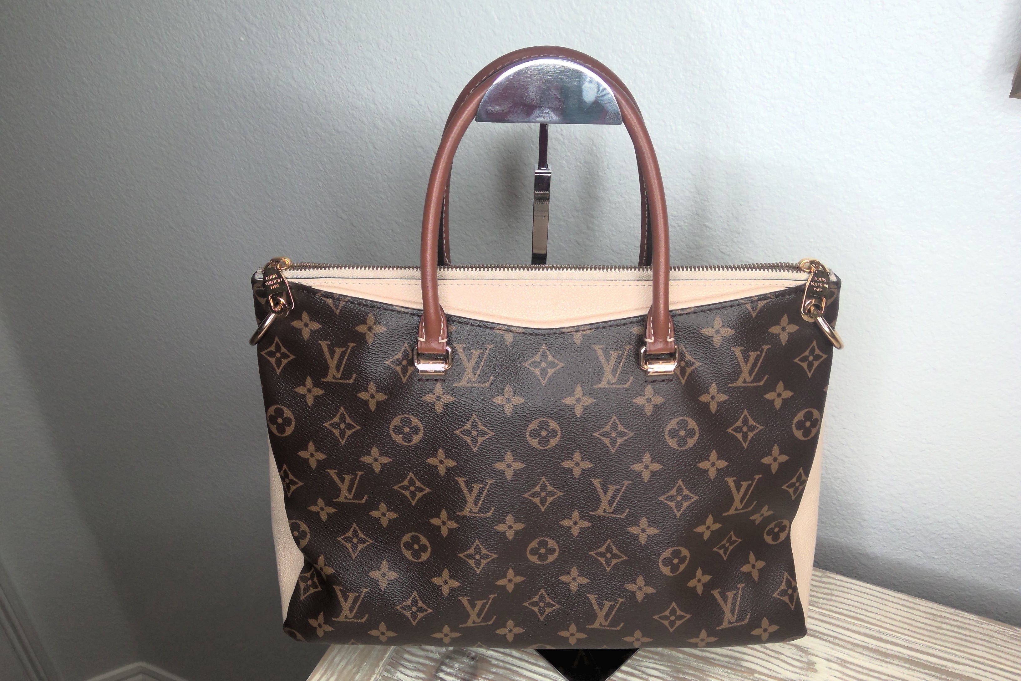 Designer handbag with monogram pattern on a neutral background