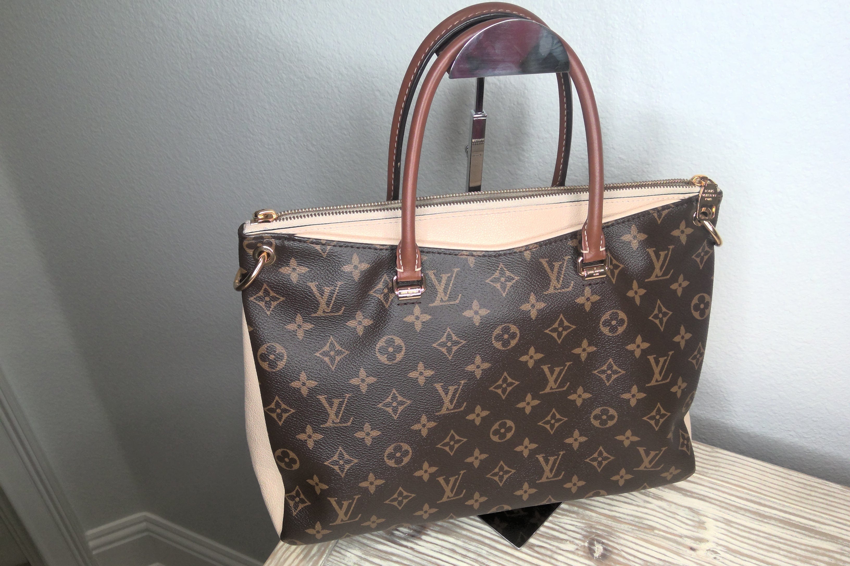 Designer handbag with monogram pattern on a neutral background