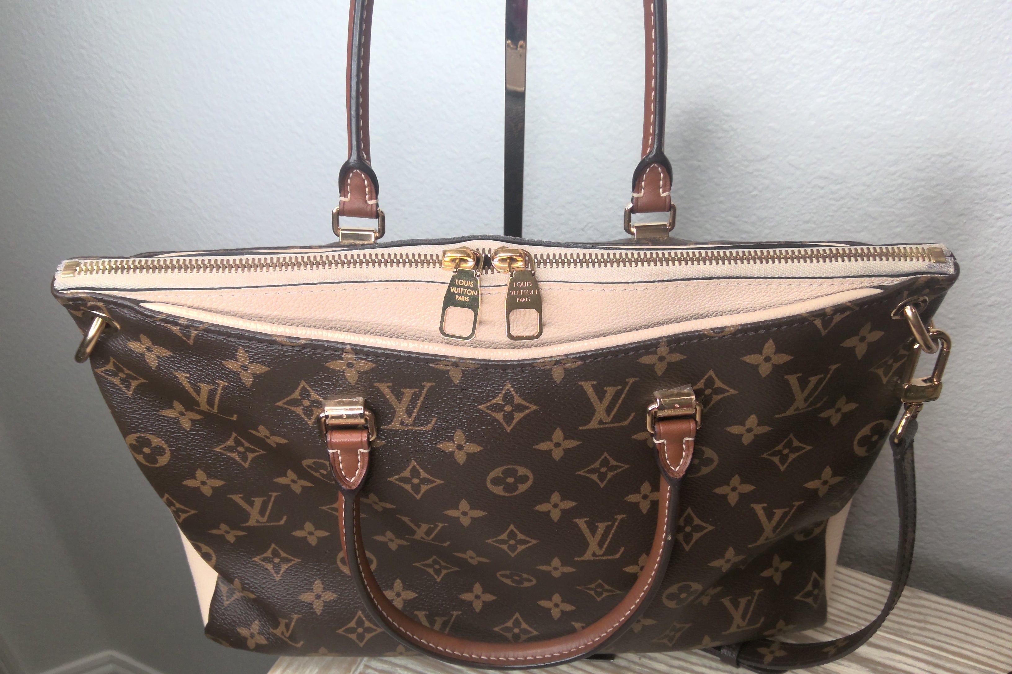 Designer handbag with monogram pattern on a neutral background