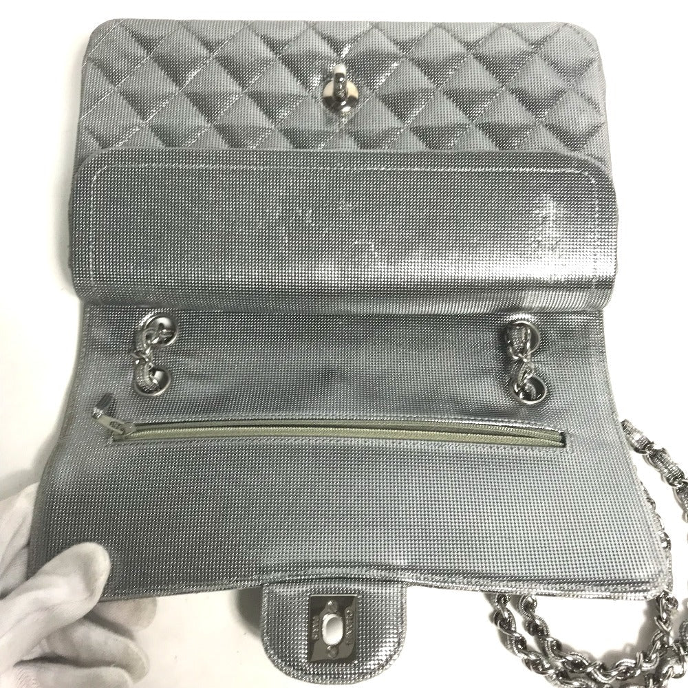 Silver quilted handbag with chain strap held by a gloved hand on a white background