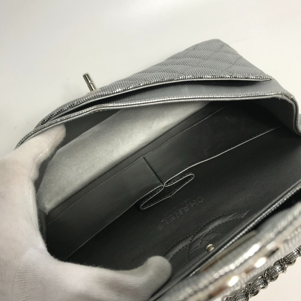 Silver clutch bag with textured surface held by a gloved hand on a light background