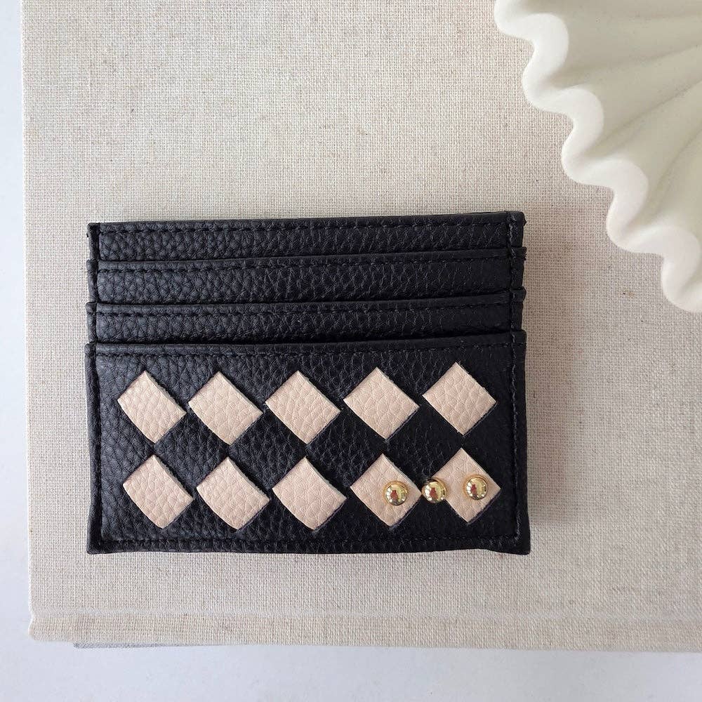Black cardholder with diamond pattern and gold accents on a beige fabric background