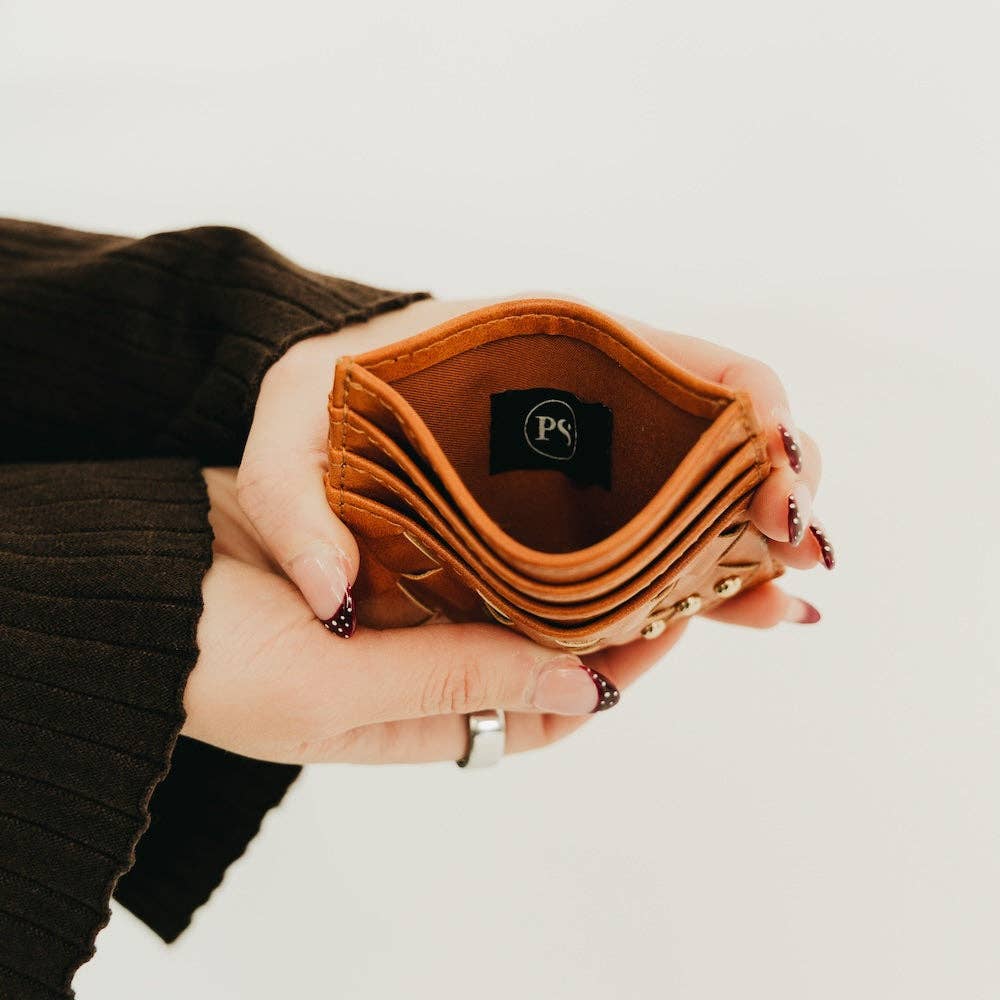 Person holding a brown wallet with a visible brand logo against a neutral background