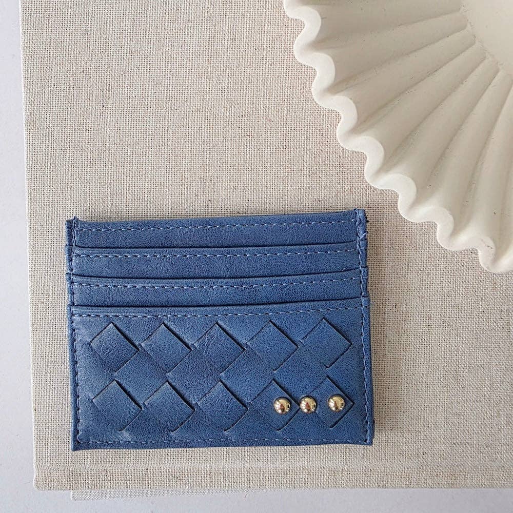 Blue woven cardholder with gold accents on a beige fabric background