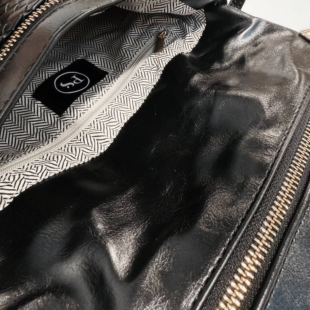 Close-up of a black leather bag with gold zipper and patterned interior.