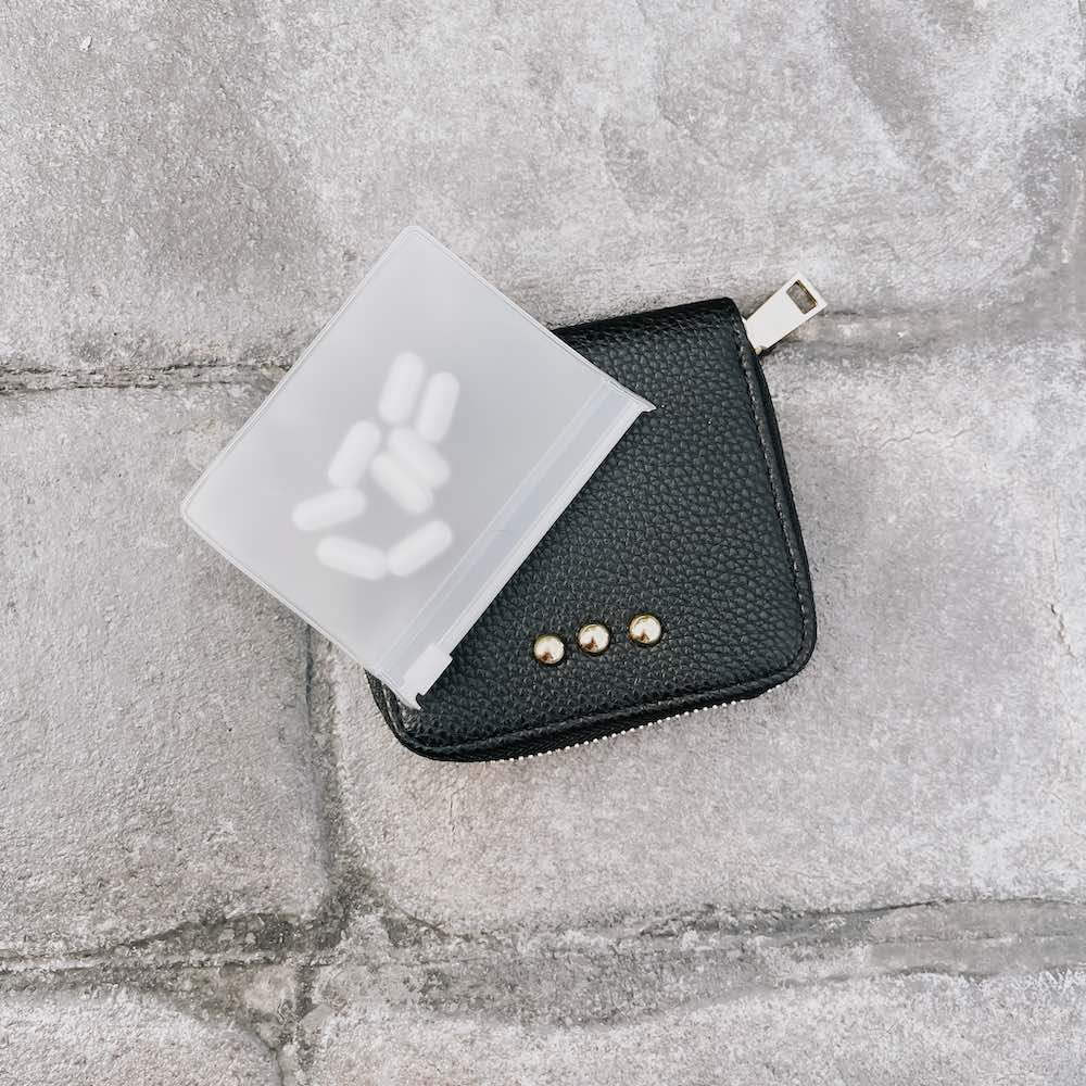 Black leather wallet with gold accents on a gray concrete surface