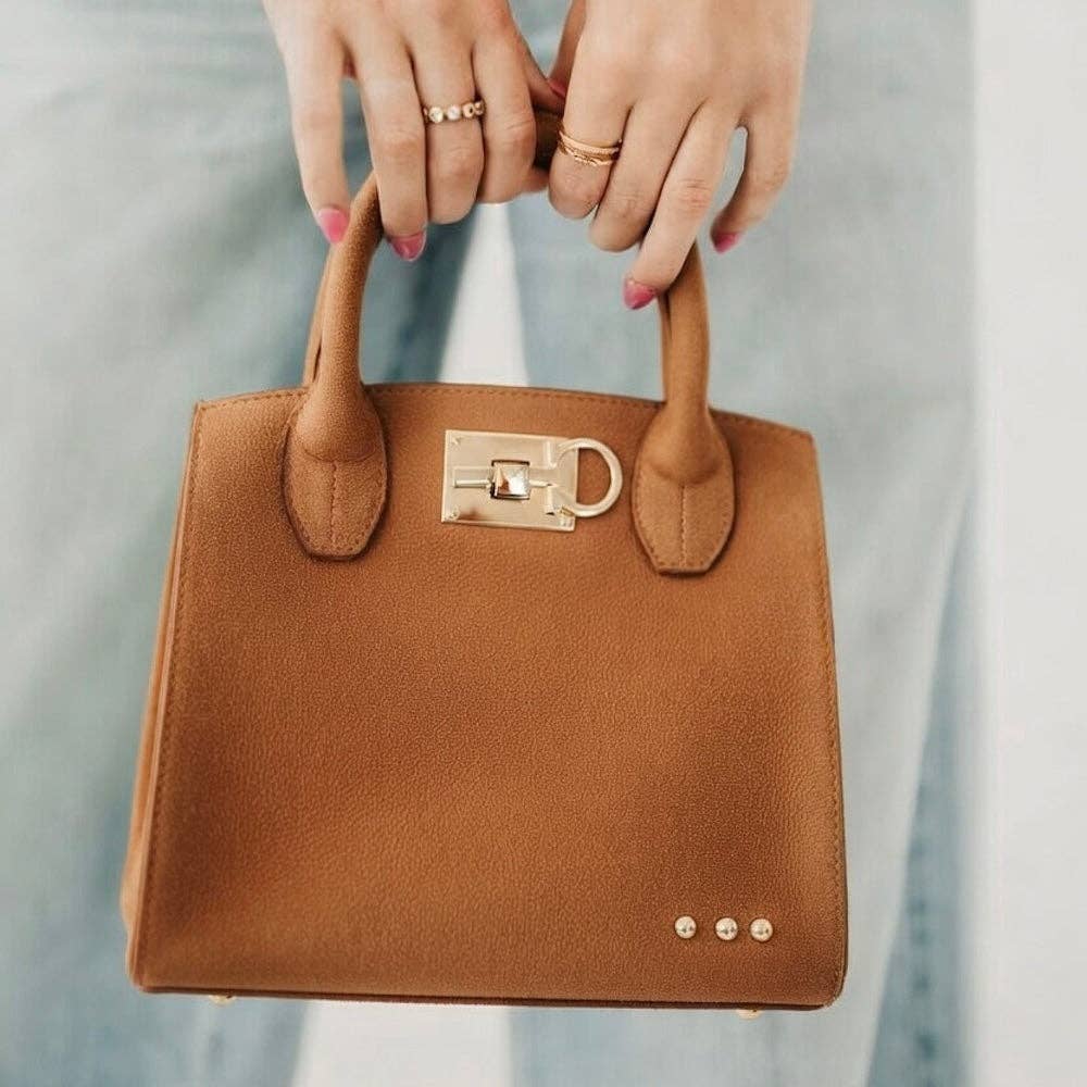 Brown handbag held by hands with a blurred background