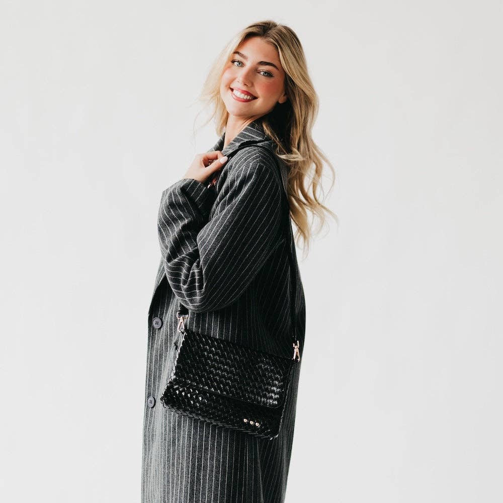 Woman holding a black textured handbag against a plain background