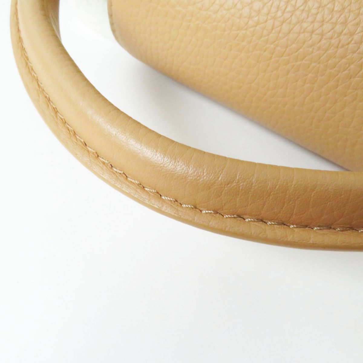 Close-up of a beige leather handbag handle on a white background