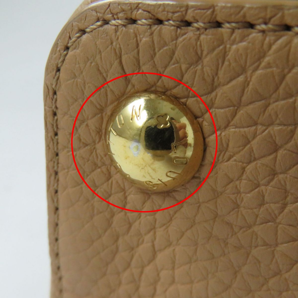 Beige leather wallet with a gold button, brand logo visible