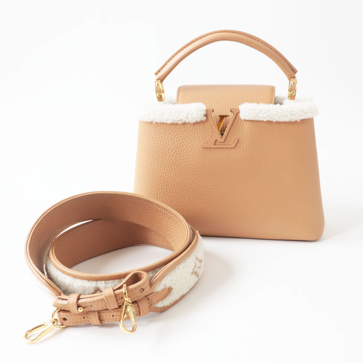 Beige handbag with white fur trim and matching strap on a white background