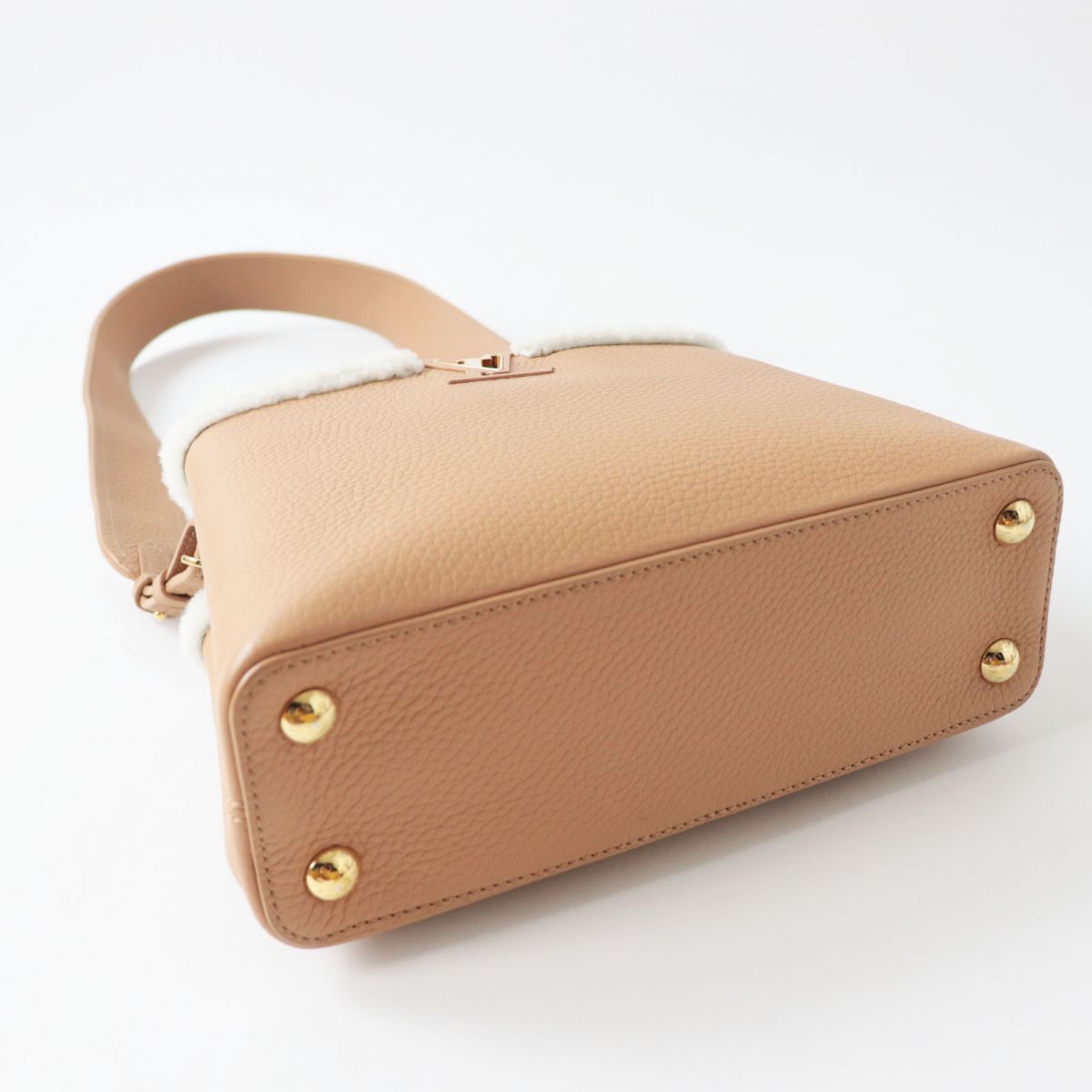 Beige handbag with gold accents on a white background