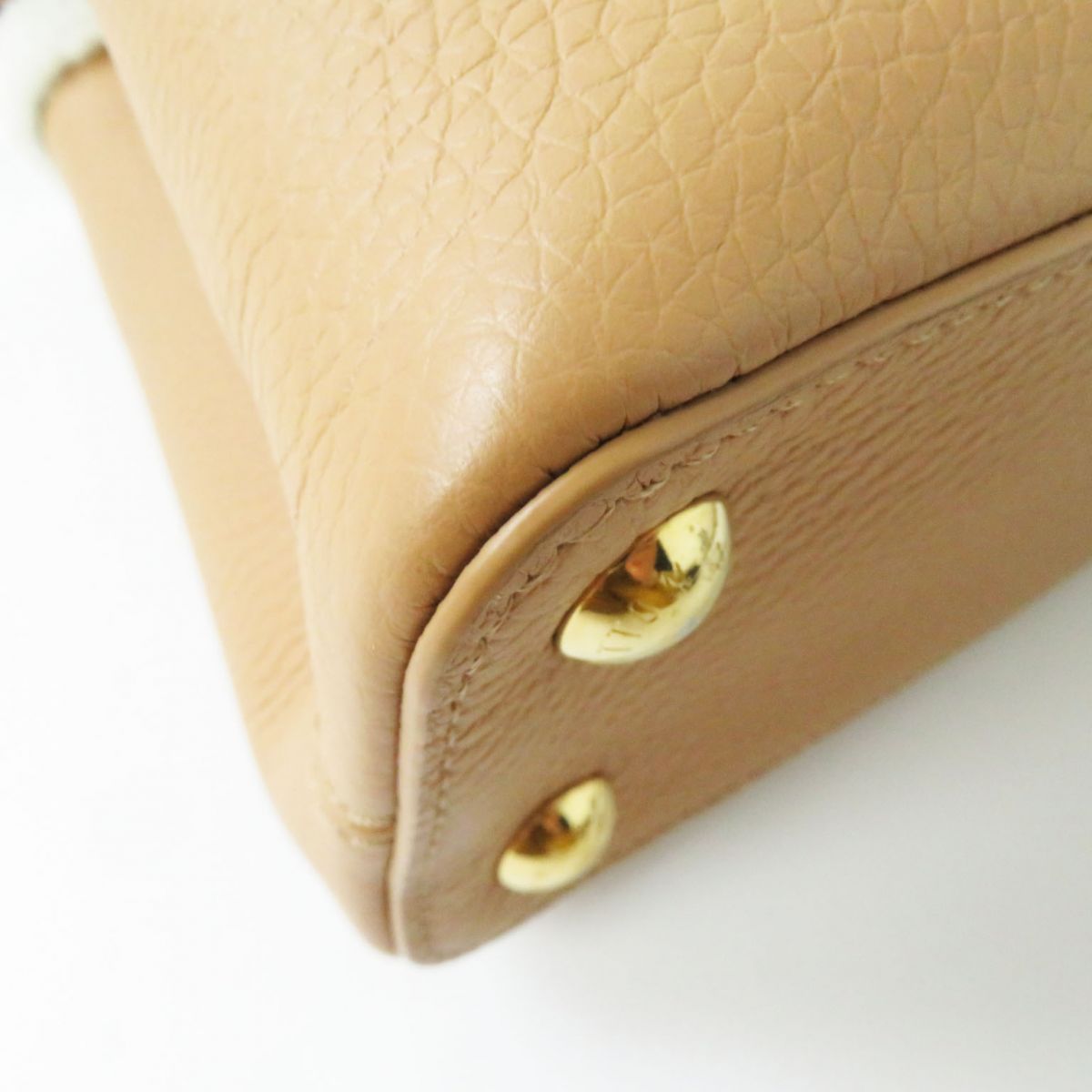 Close-up of a beige leather product with gold accents on a white background
