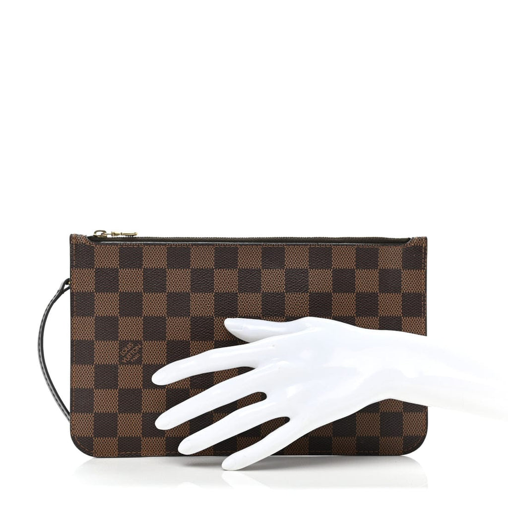 Brown checkered clutch bag with a white hand wearing a glove on a white background