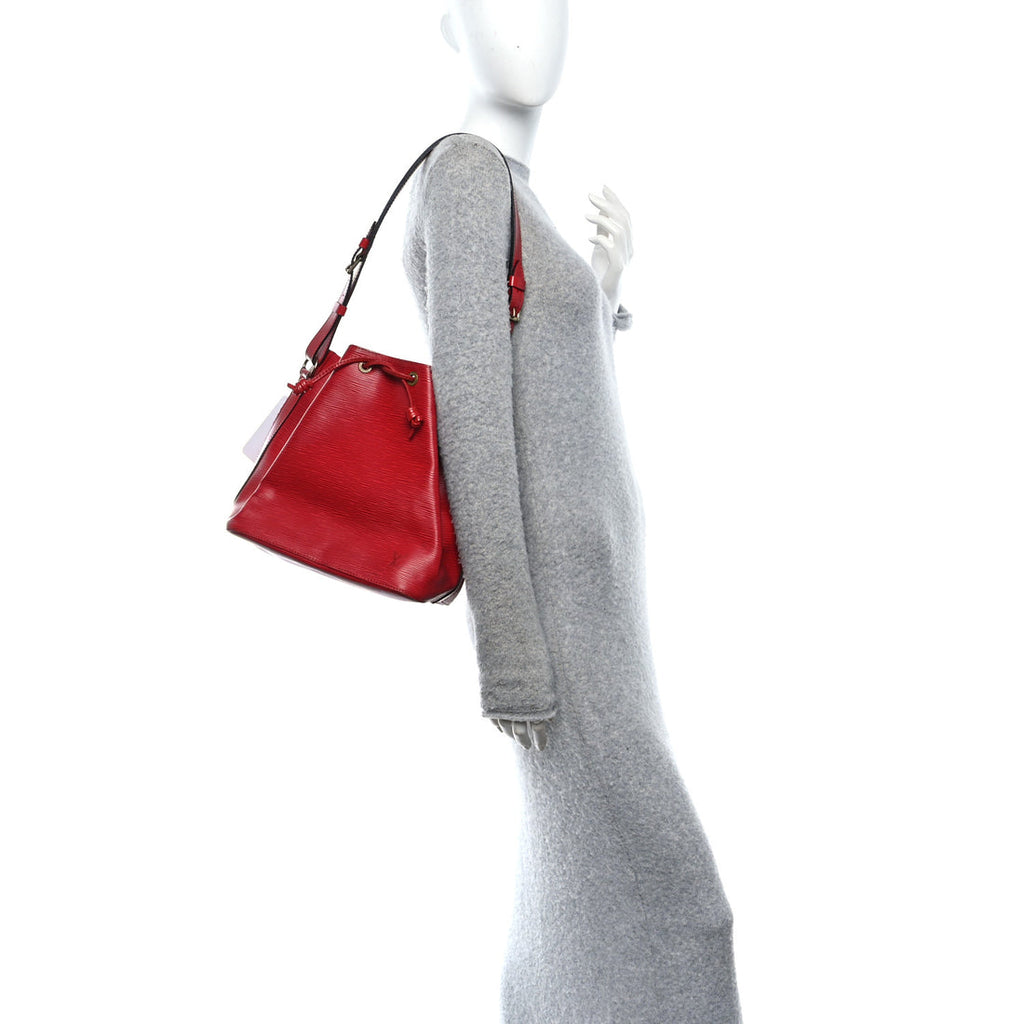Red handbag held by a mannequin against a white background