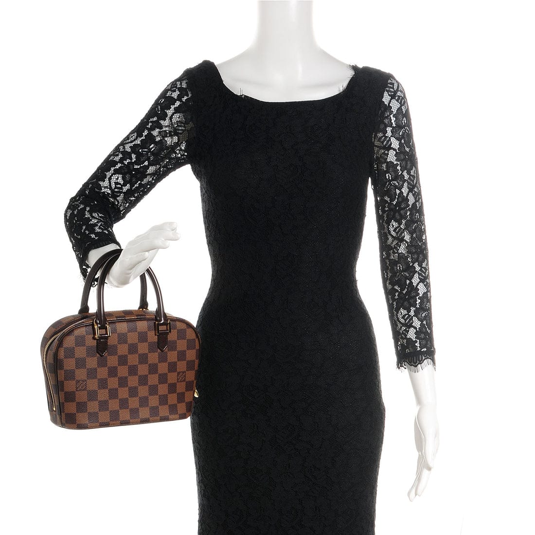 Mannequin wearing a black dress with lace sleeves holding a brown checkered handbag.