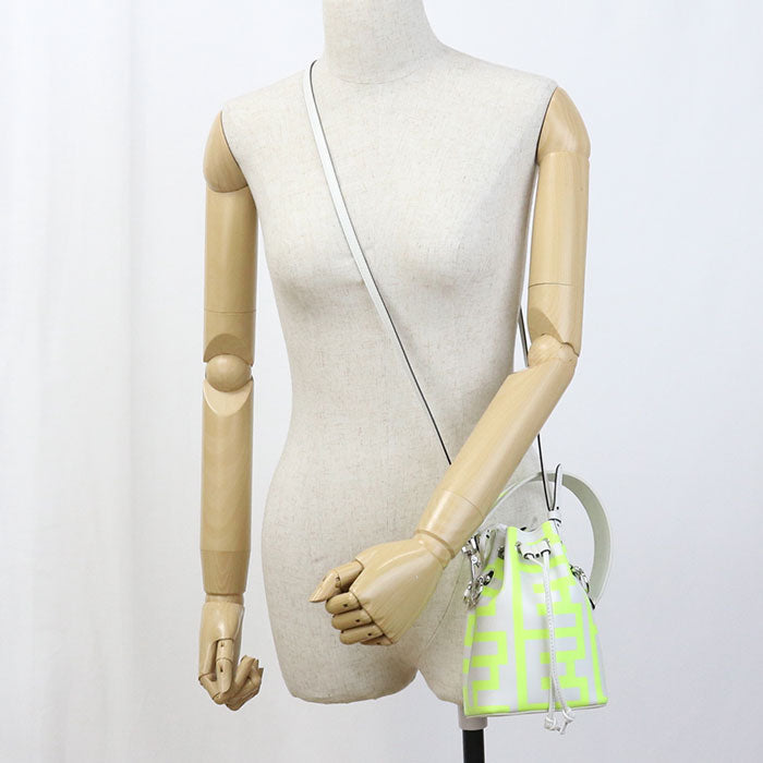 Mannequin wearing a neon green handbag with a white strap on a plain background