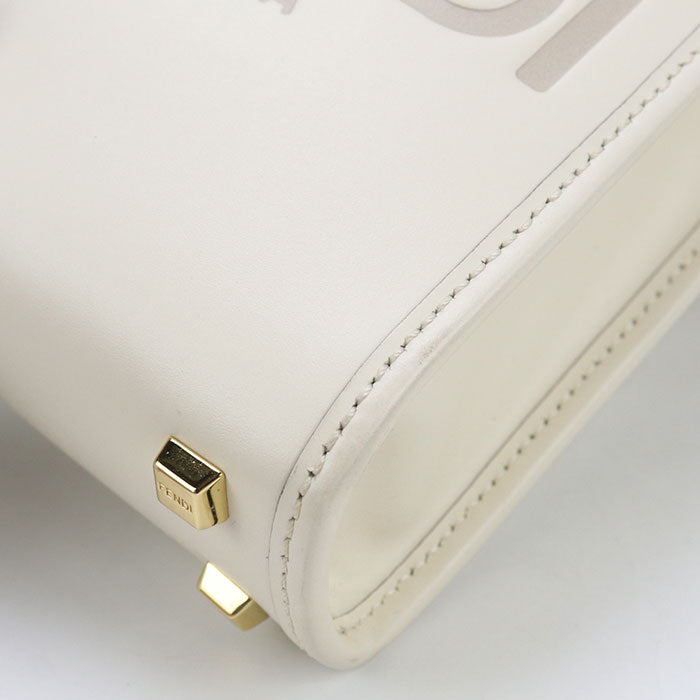 Close-up of a white handbag with gold accents on a light gray background
