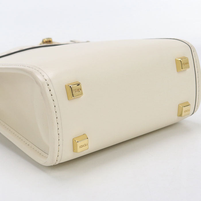 White handbag with gold accents on a light gray background