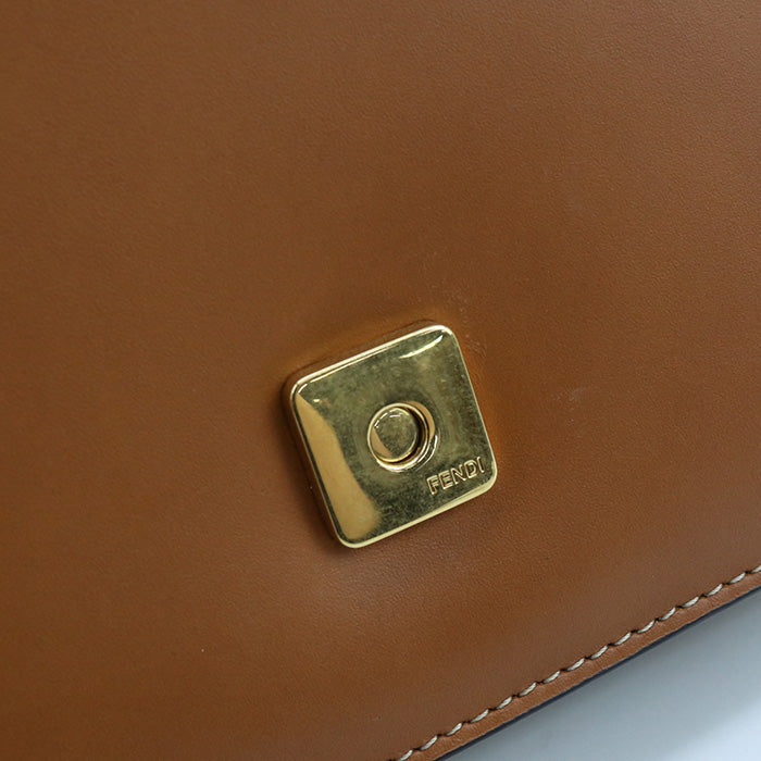 Close-up of a brown leather product with a gold logo on a light gray background