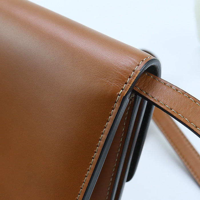 Close-up of a brown leather bag with visible stitching on a white background
