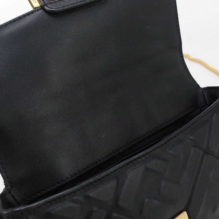 Close-up of a black handbag with textured surface and visible brand logo.