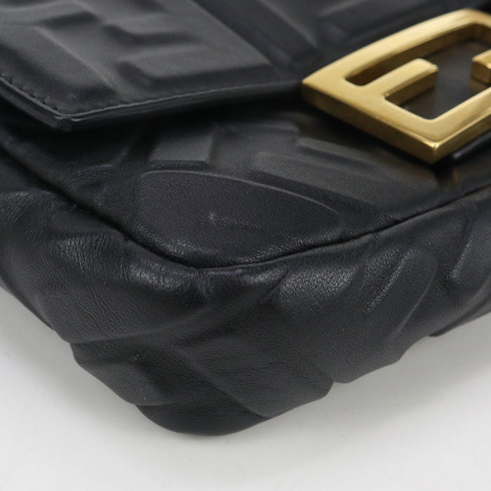 Black textured handbag with a gold clasp on a light gray background