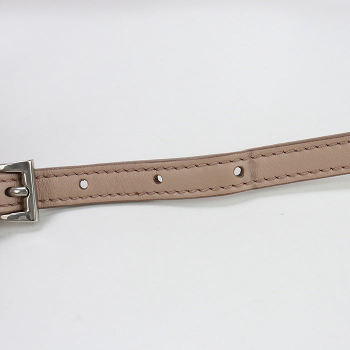 Close-up of a beige leather belt with a silver buckle on a light gray background