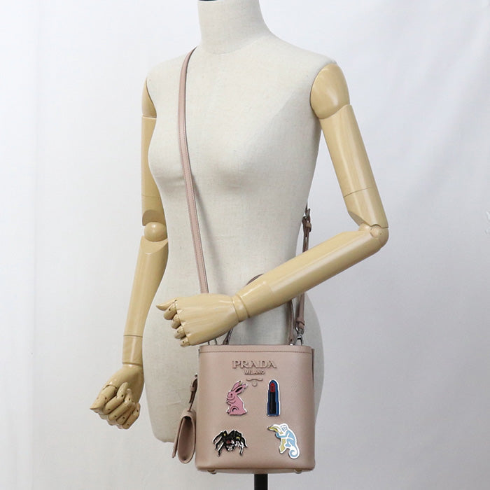 Mannequin wearing a Prada handbag with colorful patches on a white background