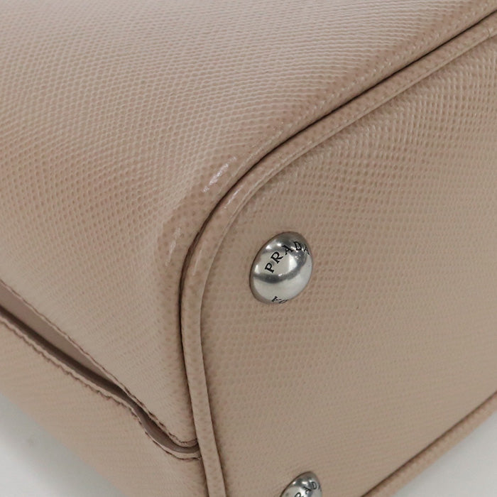 Close-up of a beige handbag with a Prada logo on a light background
