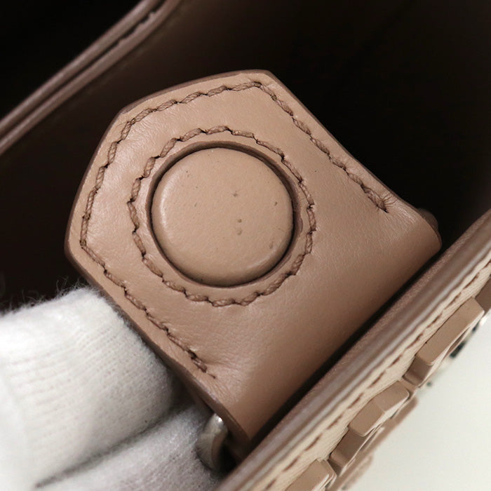 Close-up of a brown leather case with a circular button on a white surface.