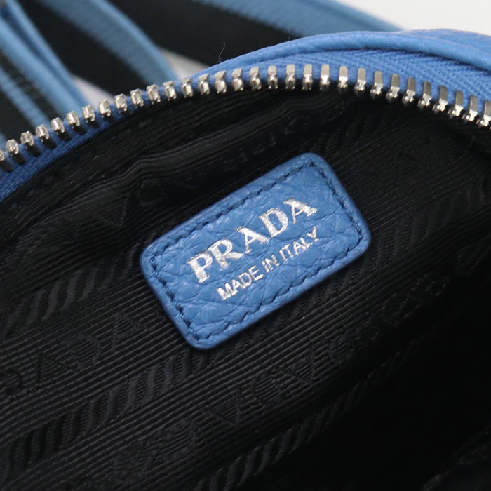 Close-up of a Prada bag with a blue tag on a black background