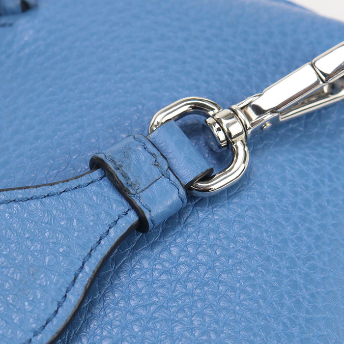 Close-up of a blue leather handbag with a silver buckle.