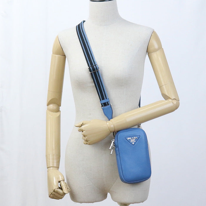 Blue crossbody bag on a mannequin with a white background